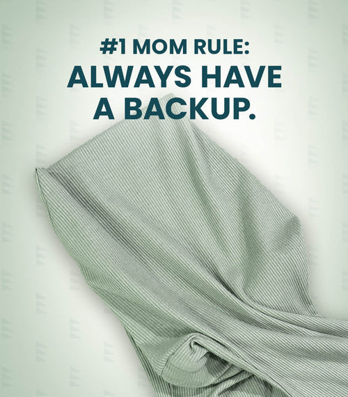 Acute Baby Co. folded ribbed knit garment in a pale sage green color, shown with a dark teal text overlay that reads '#1 MOM RULE: ALWAYS HAVE A BACKUP.' on a light off-white background with a subtle repeating watermark pattern.