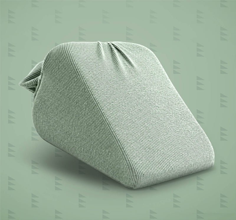 A light sage green textured fabric wedge pillow, shown on a matching sage green background with a subtle repeating watermark pattern.