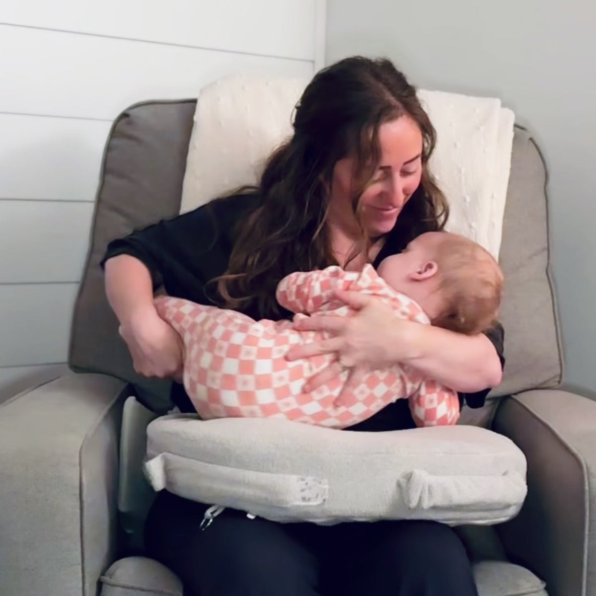 A woman breastfeeding a baby with the Acute Baby Co Wedge under the nursing pillow for added support, height, and comfort. 